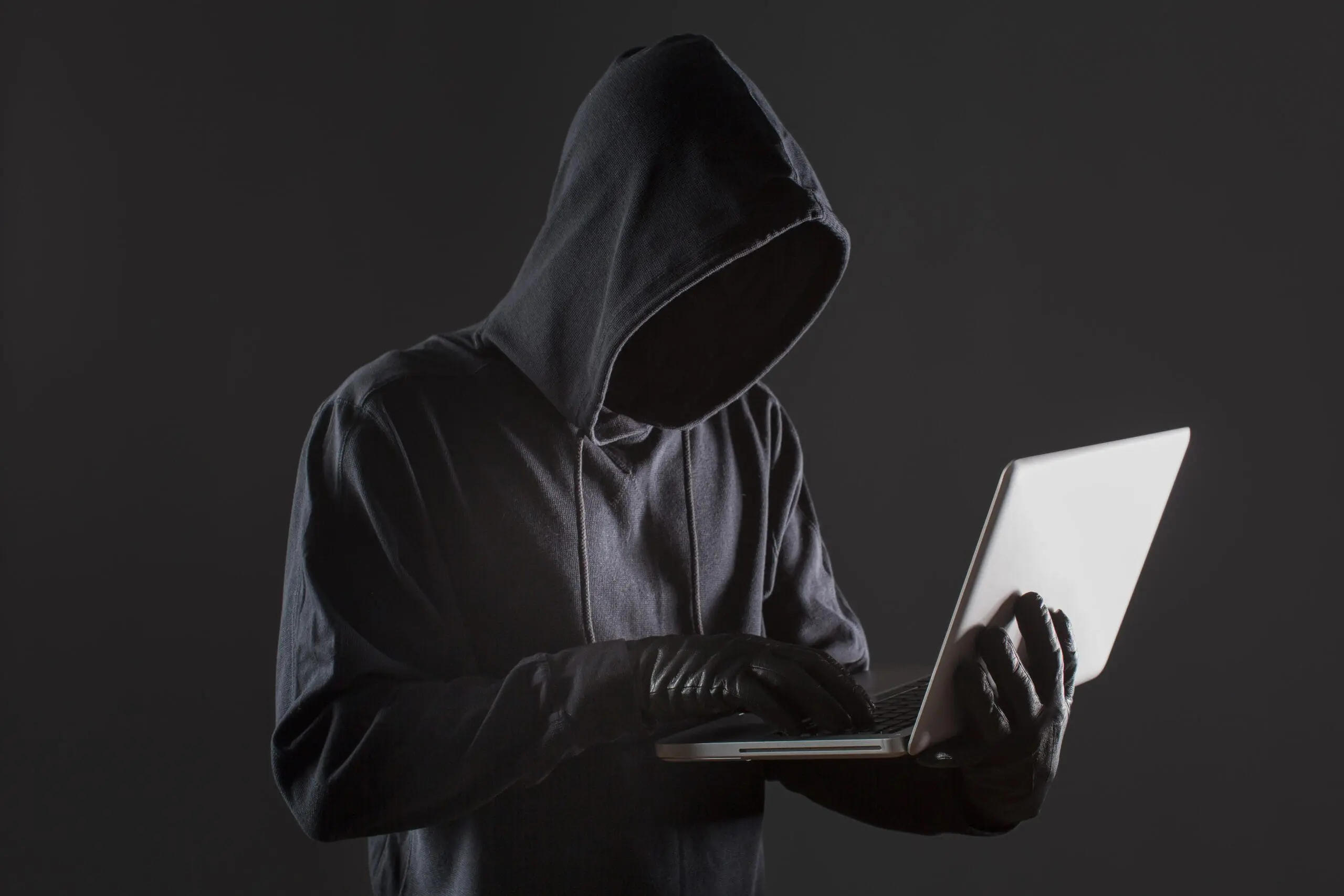 side-view-of-male-hacker-with-gloves-and-laptop