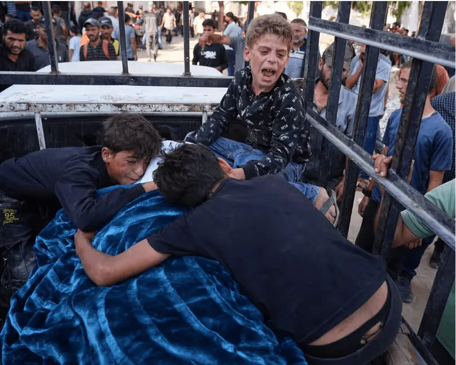 Crianças palestinas choram sobre o corpo do pai morto a caminho de um centro de distribuição de alimentos em Gaza.