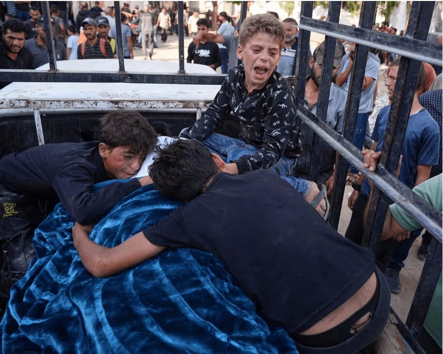 Crianças palestinas choram sobre o corpo do pai morto a caminho de um centro de distribuição de alimentos em Gaza.