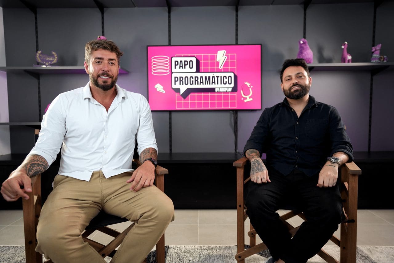 executivos posam sentados em frente à tela com logo do podcast Papo Programático