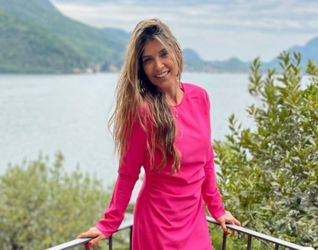 Escritora Carmen Alves de vestido rosa em homenagem ao Outubro Rosa ´posa em um lago